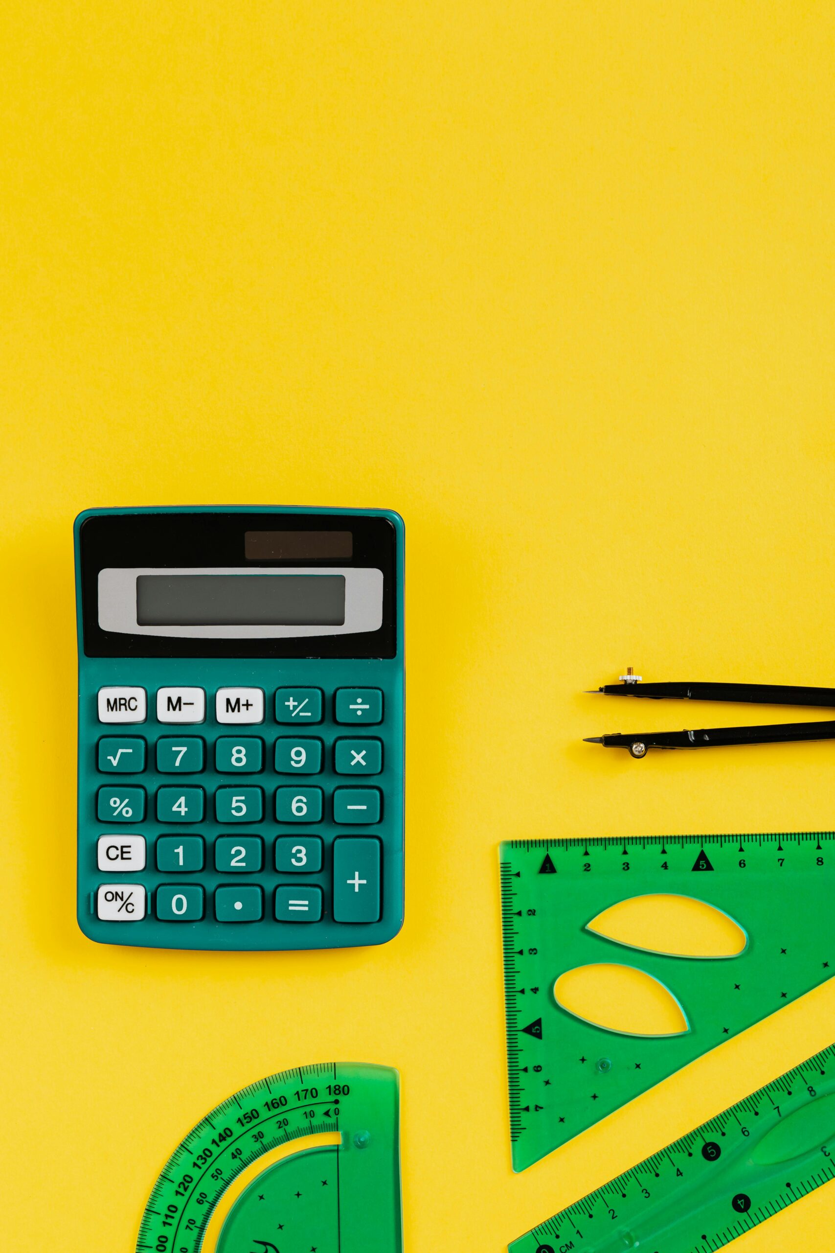 A teal calculator and green geometry tools on a vibrant yellow backdrop.