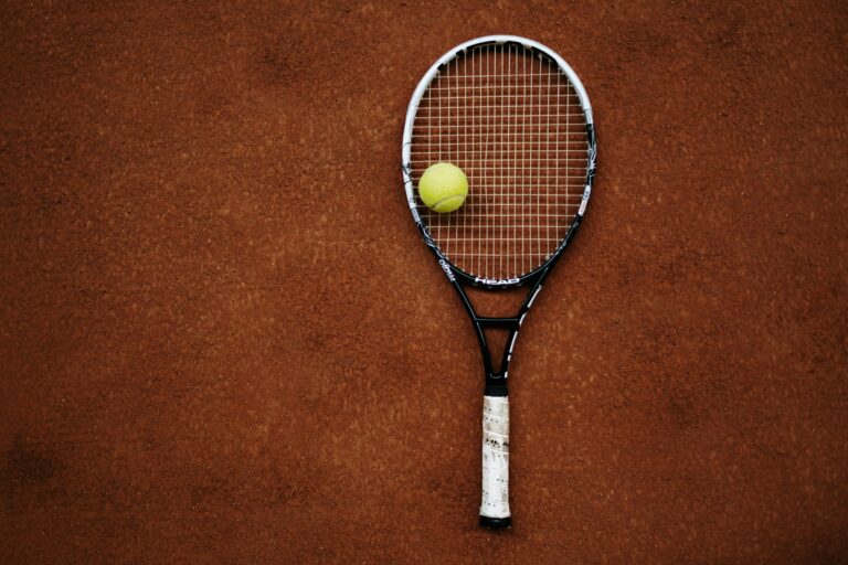 Tennis racket and ball on clay court, perfect for sports imagery.